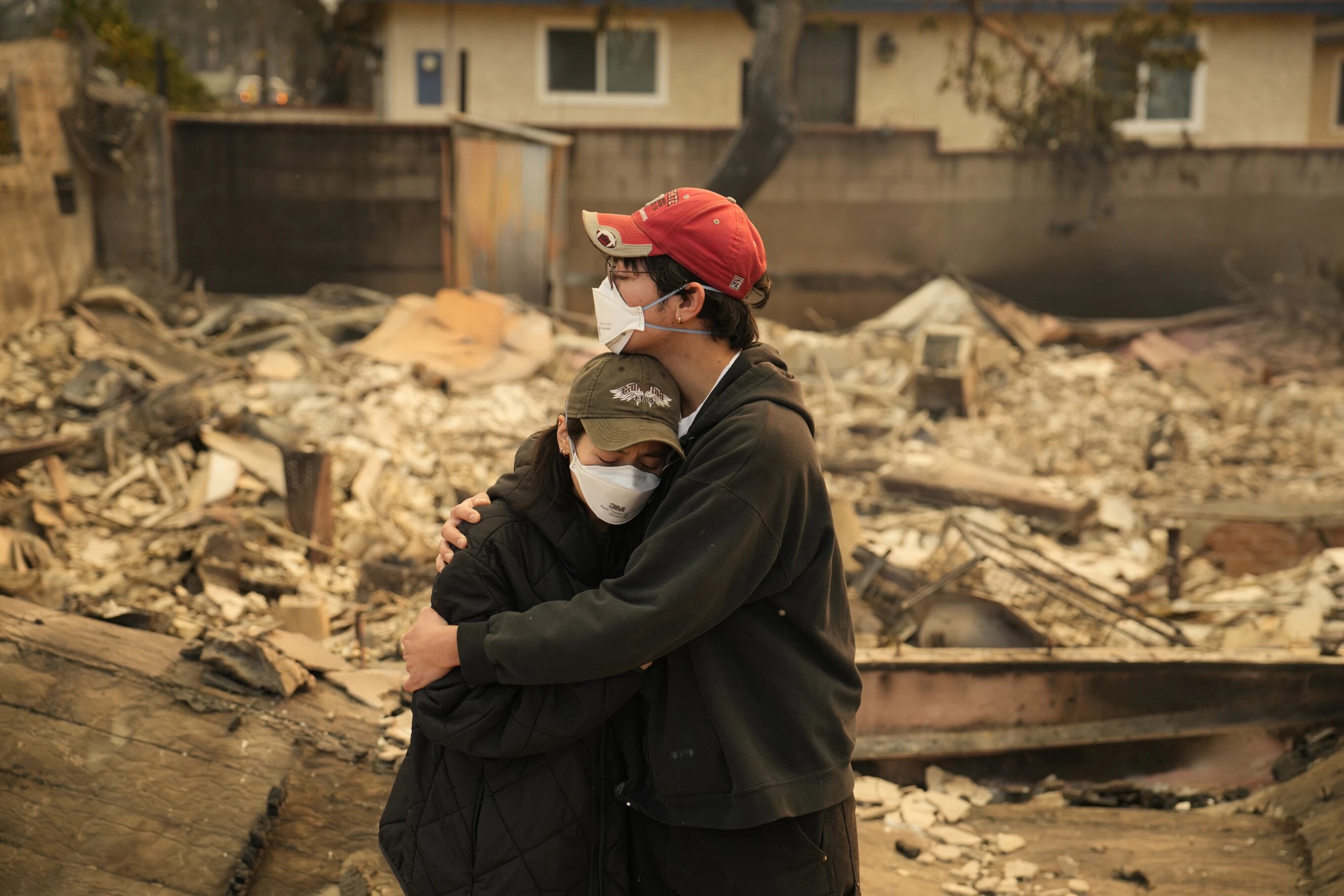 A family embraces in front of their destroyed home in Altadena, California, on Thursday, January 9, 2025.