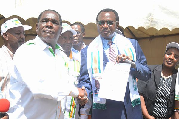 Democratic Party chairman Esau Kioni (left) hands a nomination certificate to Othaya parliamentary aspirant Peter King’ara at the Baden Powell grounds in Nyeri Town on April 30, 2017. Mr Kioni said the party will field over 350 candidates in the August elections.