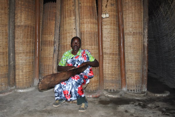 At the entrance of the palace is an old man sitting on the traditional stool performing Inanga (a traditional musical instrument).