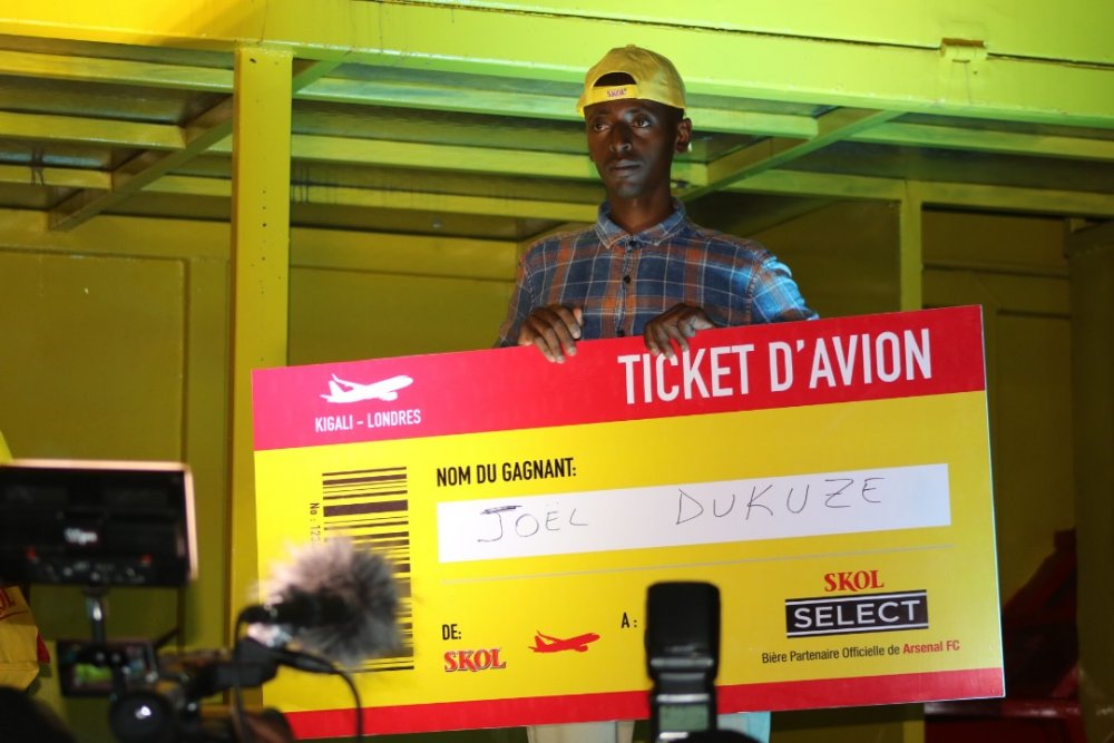 Dukuze holding his flight ticket won in 2019 as he poses for a photo.