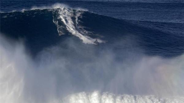 A surfer rides a huge wave at Praia do Norte at Nazare, Portugal