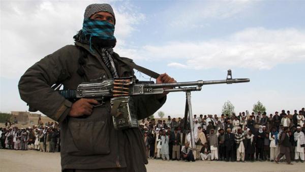 A Taliban fighter stands at the site of a public execution of three men in Ghazni province in 2015