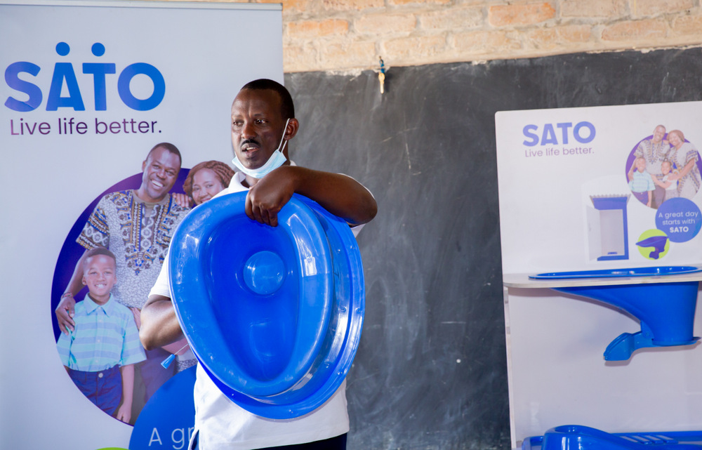 Ntaganira showcasing one of toilet pans available at Sato Rwanda.