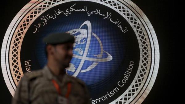 A security officer stands guard in front of the logo of the Saudi-led Islamic Military Counter Terrorism Coalition