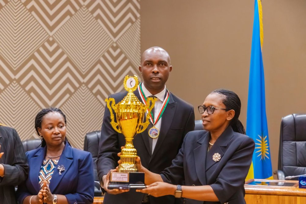 The Captain of the Volleyball Team presents the trophy they won to Kazarwa Gertrude, Speaker of the Rwandan Parliament, Lower House.