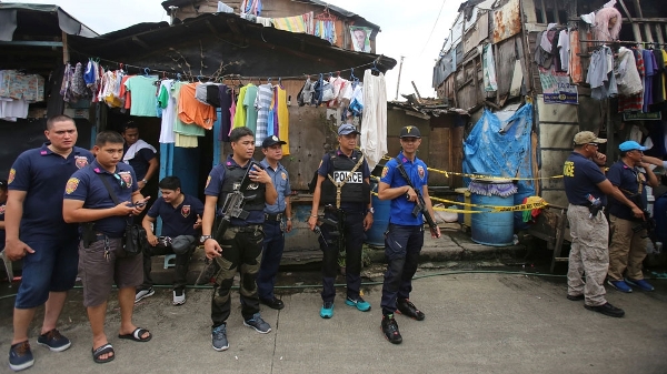 Philippine police stand on guard during a raid in a slum area in Metro Manila
