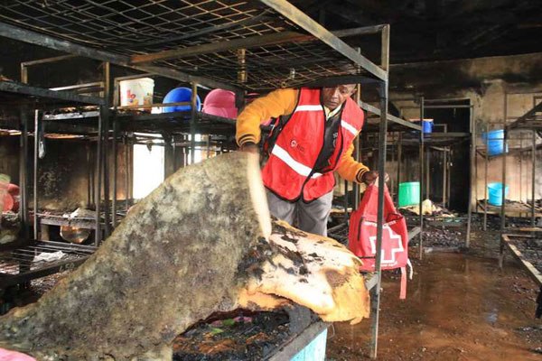A Kenya Red Cross volunteer inspects a dormitory at Giakaibii Boys High School in Nyeri after it was destroyed by a fire on July 20, 2016.