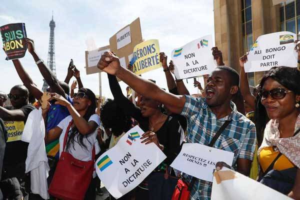 People hold placards reading "no to the dictatorship", during a demonstration in support to the Gabonese people, at the Esplanade du Trocadero in Paris, on September 3, 2016. Experts says electoral fraud in Africa is becoming harder, thanks to civil society vigilance and spread of mobile technology.