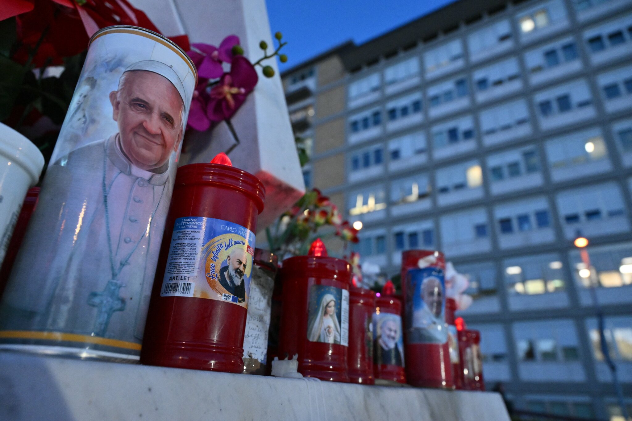 Candles are laid at the statue of John Paul II outside the Gemelli hospital where Pope Francis is hospitalized in Rome on February 22, 2025.