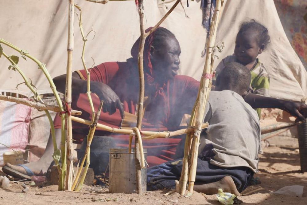 A woman prepares food for children at a displacement camp in El Fasher, North Darfur region, Sudan, on July 9, 2025. (UNICEF/Handout via Xinhua)