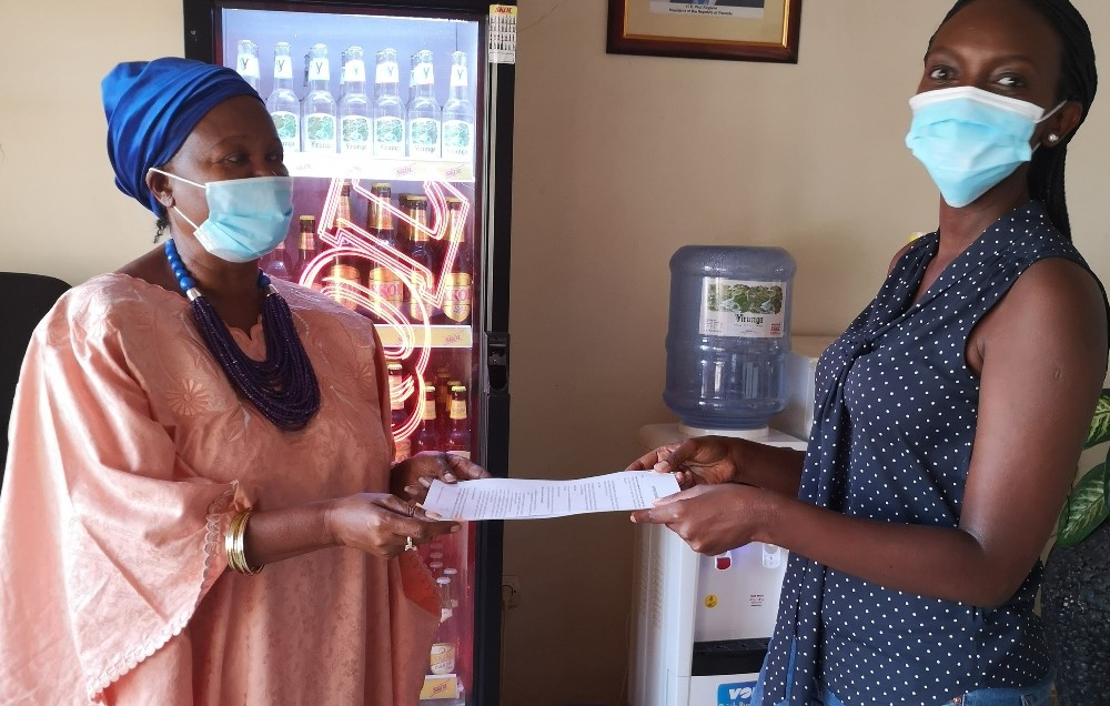 The President of Gira Impuhwe, Drocella (left) exchanging documents with a representative from SKOL.