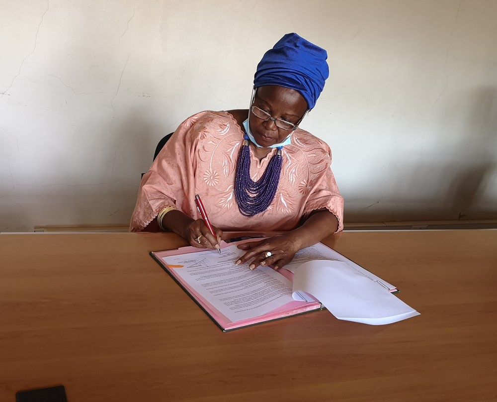 The President of Gira Impuhwe, Drocella signing the financing agreement. 