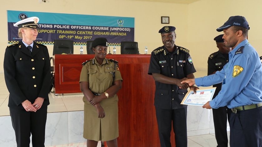 CP Vianney Nshimiyimana, the commandant of PTS giving a certificate of attendence to one of the course participants.