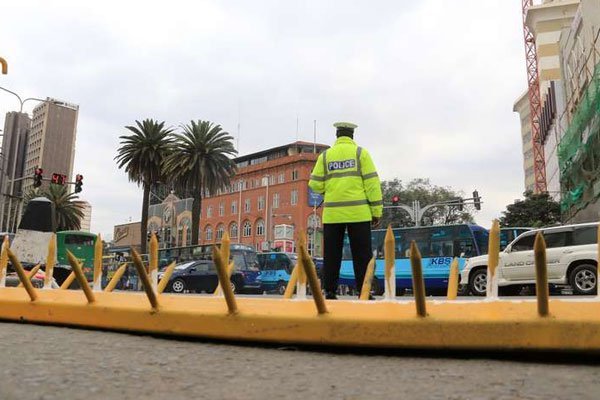 A traffic police officer stands next to a barrier on the Kenyatta Avenue/Kimathi Street junction in Nairobi on August 27, 2016. A traffic police officer is expected to appear in an Embu court after he was arrested for allegedly soliciting a bribe.