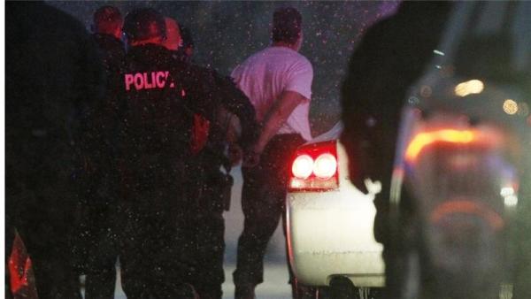 The handcuffed gunman is moved to a police vehicle in Colorado Springs