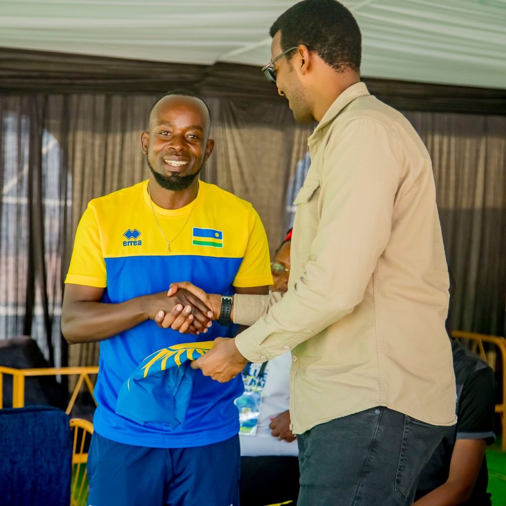 The Minister of State in the Ministry of Sports, Rwego Ngarambe, hands over the national flag to the coach of the Rwanda men’s national tennis team, Habiyambere Dieudonné.