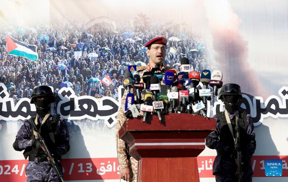 Houthi military spokesperson Yahya Sarea (at the podium) makes a statement during a rally in Sanaa, Yemen, on Dec. 13, 2024. Yemen's Houthi group said in a statement on Friday that they had launched multiple drone attacks targeting "Israeli targets." (Photo by Mohammed Mohammed/Xinhua)