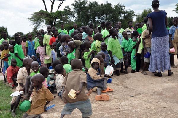 A teacher of Rainbow Primary School in Moroto District organises pupils in a queue at lunch.