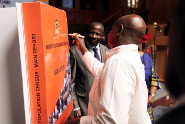 President Museveni appends his signature to the 2014 population and housing census report at Kampala Serena Hotel yesterday as Finance minister Matia Kasaija looks on.