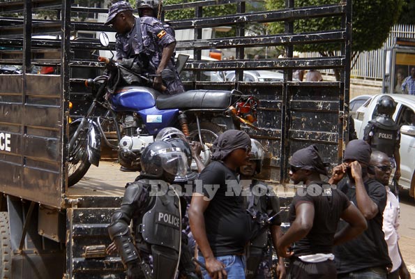 Masked men alongside police officers near a police truck in Kampala on Tuesday.