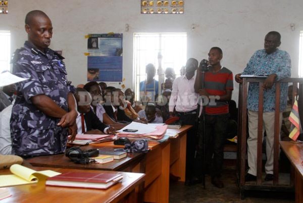 Senior Superintendent of Police David Ulama (L) addresses court during a hearing at the Kasangati Magistrates Court in Wakiso District, yesterday. Standing extreme right is Dr Kizza Besigye.
