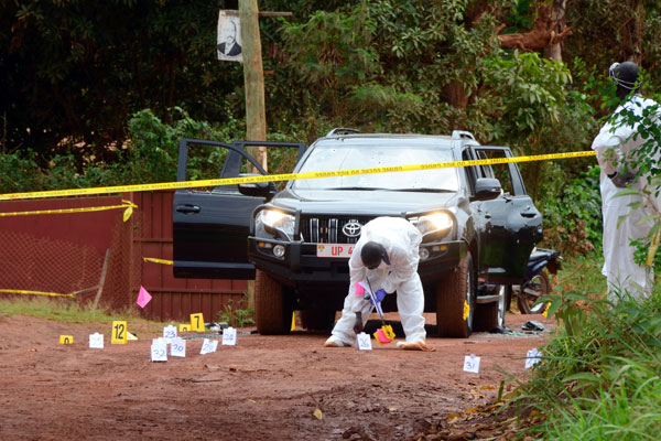 On duty. Police forensic officers comb the scene where AIGP Felix Kaweesi was gunned down by unknown assailants yesterday morning.