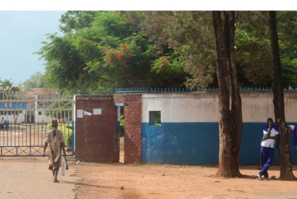 Students stand outside the fence after being sent home following a strike at Lango College, Lira Town, on Wednesday.