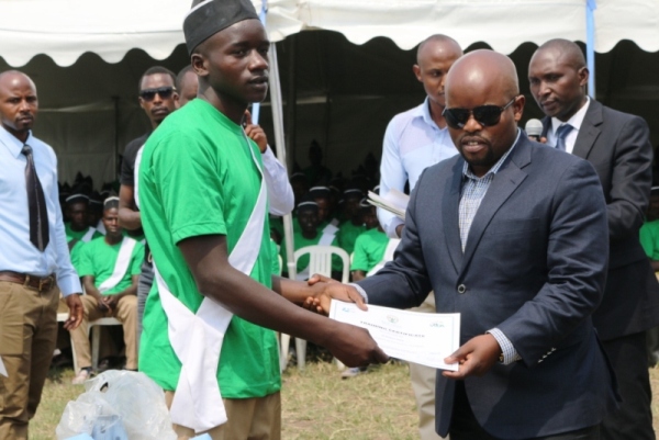 The Minister of Youth and ICT, Nsengimana Jean Philbert handing a certificate to Iwawa graduate 