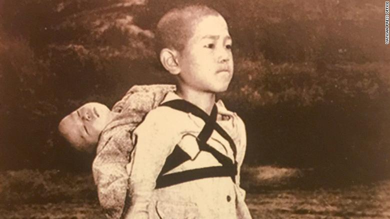 The photo captures a boy carrying his dead brother on his shoulders while he waits for his turn at the crematory.