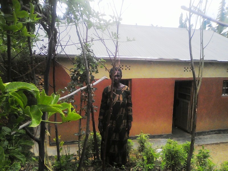 Mukamana Laurence standing in front of the house she built after maximizing benefits of donated cow from Girinka program