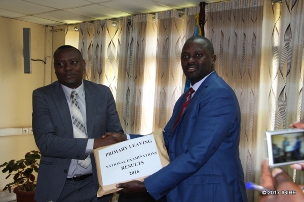 The State Minister in Charge of Primary and Secondary schools, Isaac Munyakazi handing examination results to the Director General of Rwanda Education Board, Janvier Gasana.