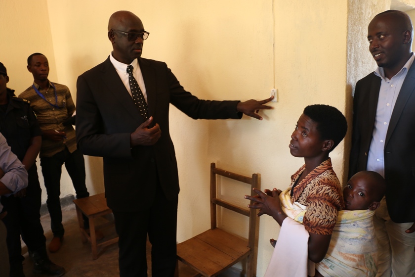 Minister Johnston Busingye switches on light in one of the houses to launch solar energy in Jali.