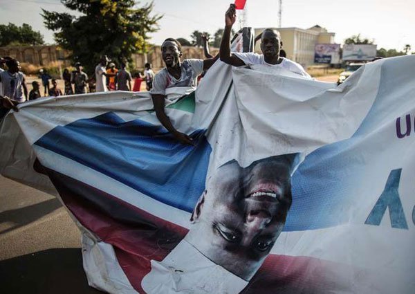 Supporters of the newly elected Gambia's President Adama Barrow tear down posters of the incumbent Yahya Jammeh in Serekunda on December 2, 2016.