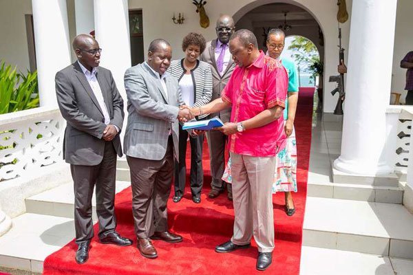 Education Cabinet Secretary Fred Matiang’i presents a copy of the KCSE examination report to President Uhuru Kenyatta at State House, Mombasa, on December 29, 2016. Present were PS Belio Kipsang (left), Knec chairman George Magoha and acting CEO Mercy Gathigia (right) and Teachers Service Commission boss Nancy Macharia.