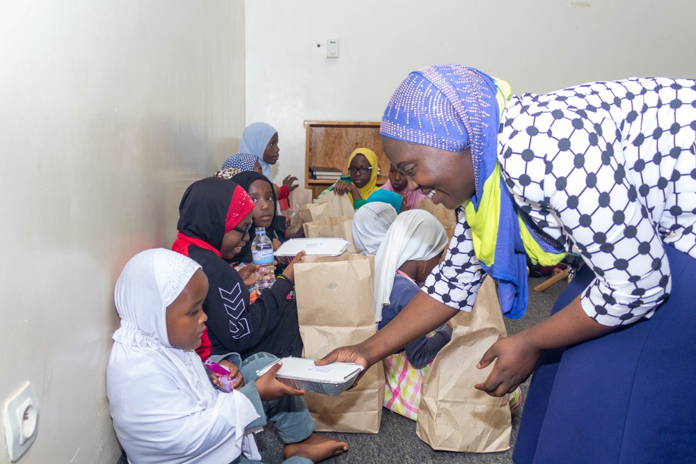 Kigali Marriott’s Human Resource Manager Aisha Nante Mambo serves meals to children in the mosque in Nyamirambo, Wednesday.