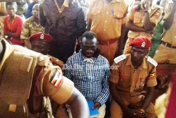 Besigye surrounded by prison warders at Nakawa Court where he re-appeared for further mention of his treason charges. Photo by Abubaker Lubowa