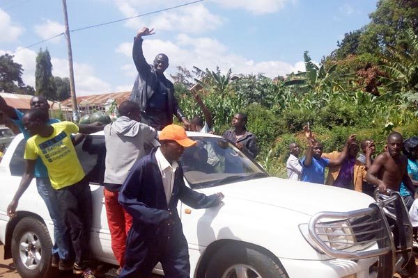 Dr Kizza Besigye waves to his supporters at Mpererwe on his way from Entebbe Airport to his home in Kasangati .