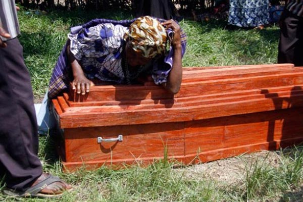 A woman weeps on the casket bearing remains of her relative outside Kasese Municipal Health Centre III mortuary.