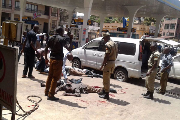 Police officers guard suspects of the shoot out at City Oil fuel station in Kamwokya.