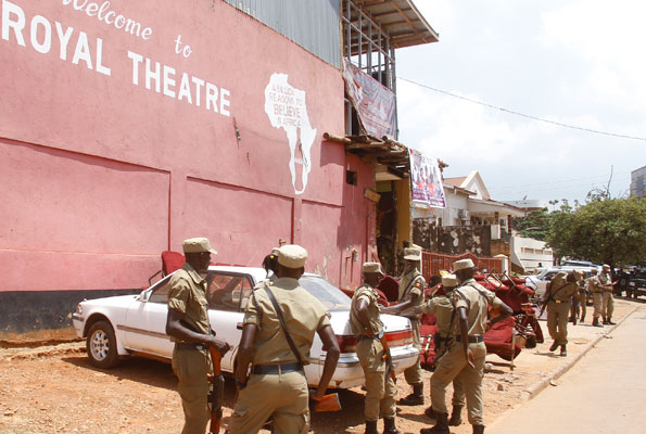 Police officers witness the eviction of Kato Lubwama's drama group from the building.