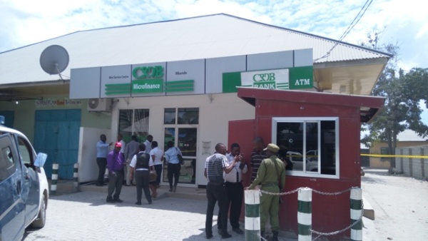 Shocked Mbande residents on the outskirts of Dar es Salaam in Temeke Municipality and newsmen gather at the scene of Tuesday evening shooting outside a CRDB Microfinance Bank branch in which four policemen were shot dead by bandits and two civilian injured. 