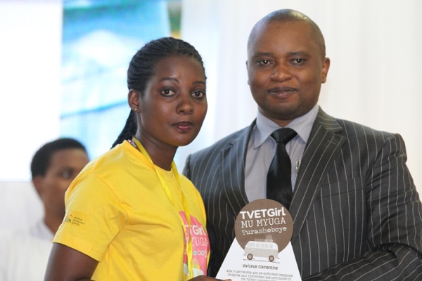 The State Minister in Charge of TVET at the Ministry of Education, Olivier Rwamukwaya handing the award to one of excellent girls in vocational trainings.