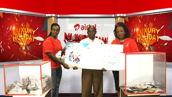 Ni ikirengaaa winner Nziyumvira Viateur in the middle holding a placard alongside Airtel Rwanda Brands and Communictions Manager ,Clementine Nyampinga