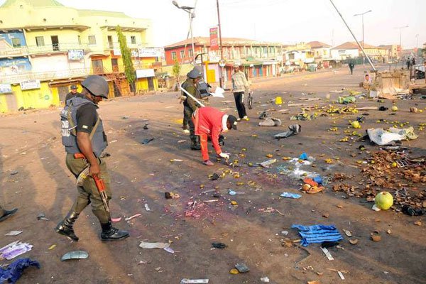 Nigerian security inspect the scene of a bomb blast at the Jos Terminus Market, on December 12, 2014. A 10-year-old died after the suicide vest she was wearing exploded outside an IDP camp in northeast Nigeria.