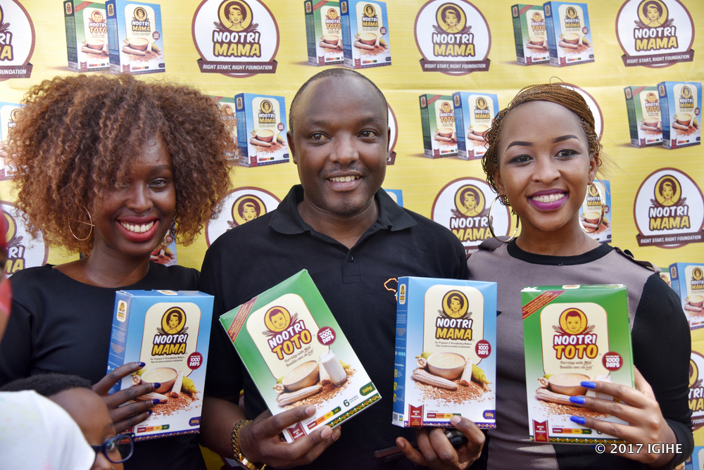 The country director of AIF in Rwanda, Prosper Ndayiragije with both female artists Charly and Ninana presenting brands of manufactured flour.