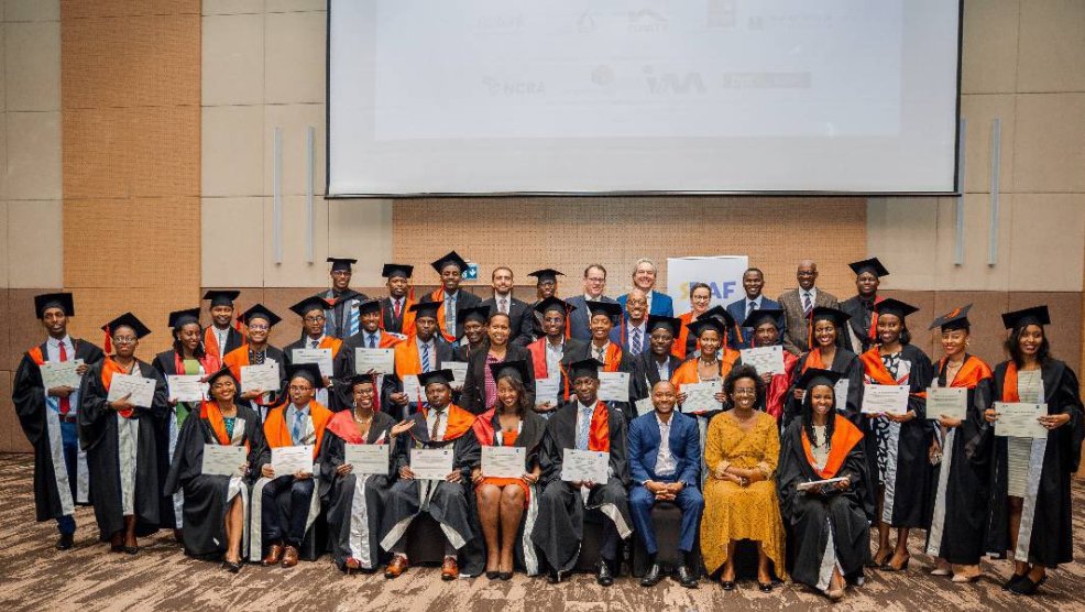 Graduates in a group photo with senior bank managers and partners. 