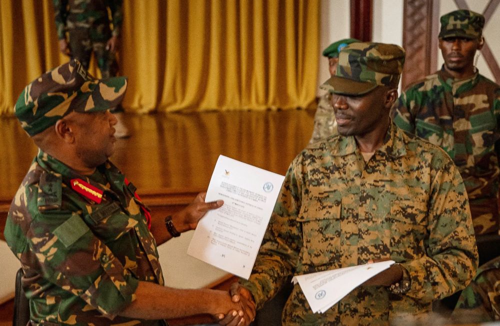 Major General Ibrahim Michael Mhona, chief of operations of the Tanzanian People’s Defence Force (left) and Sultani Makenga, M23’s military commander, shake hands after signing a withdraw deal on 28 March 2025.