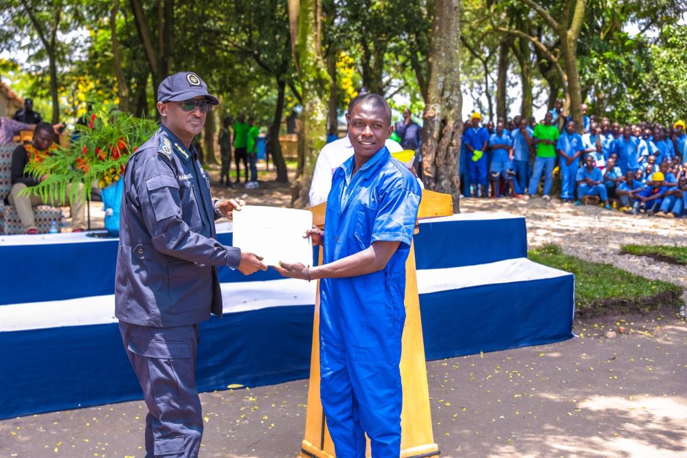 Inspector General of Police (IGP) Felix Namuhoranye hands over a certificate to one of the graduates.