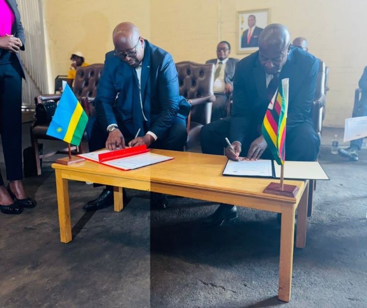 Rwanda’s Ambassador to Harare James Musoni and Minister Daniel Garwe sign documents during the event to hand over the food relief