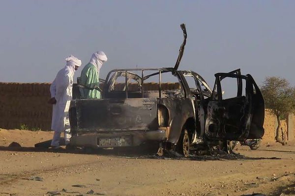 Men stand on October 8, 2016 near the wreckage of the car of a former Malian rebel group leader Cheikh Ag Aoussa after it hit a mine in Kidal. In a bid to help crush the growing jihadist threat, France has trained more than 20,000 African soldiers every year since a Paris summit in 2013.